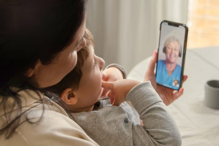 Kvinna och barn, håller i mobiltelefon