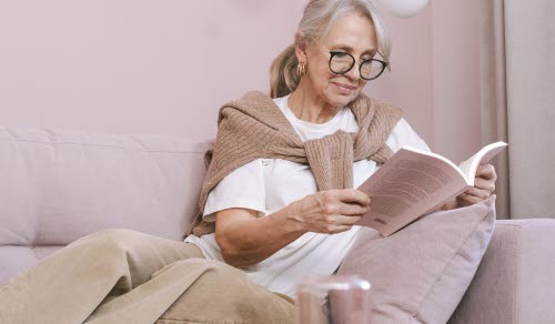 Kvinna som sitter och läser i soffa.