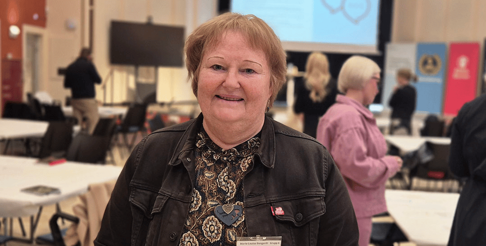 En person står i ett rum med bord och stolar.