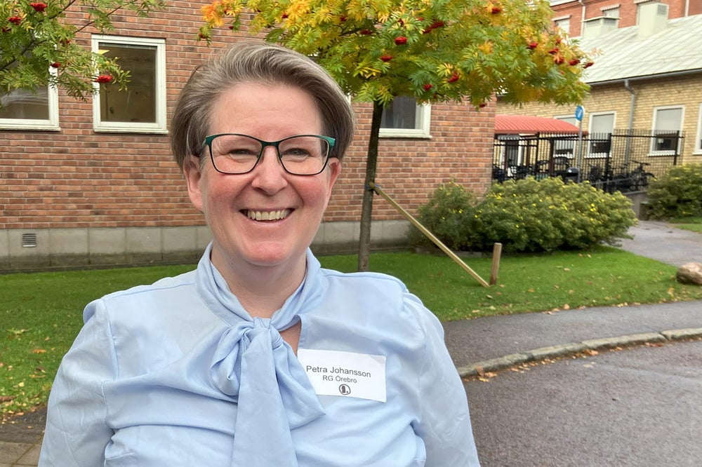Porträtt av en person med namnbricka som visar ”Petra Johansson, RG Örebro”, utomhus framför en tegelbyggnad.