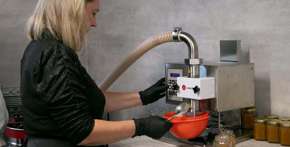 Kvinna tappar honung på burk.