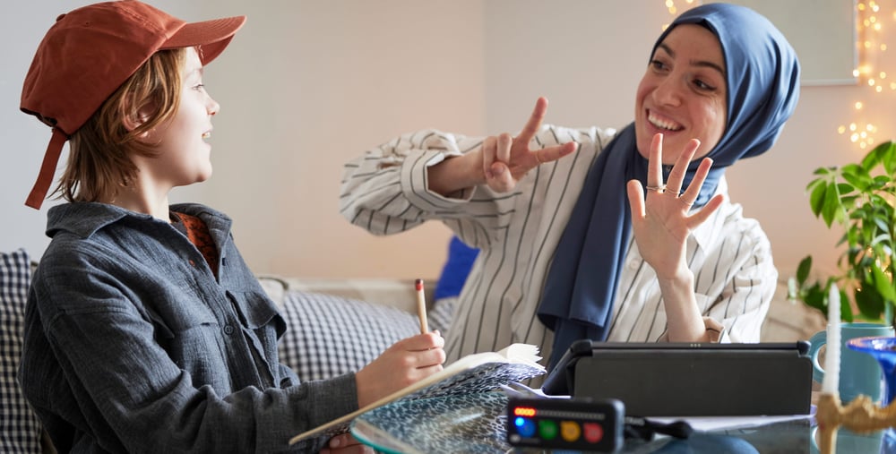 Ung kvinna med hijab hjälper pojke med läxor.