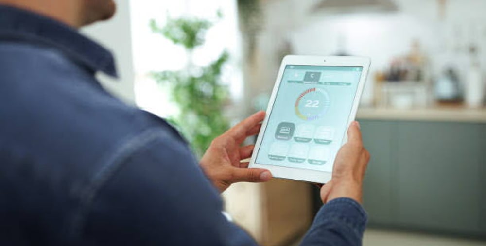 Man is Adjusting a temperature using a tablet with smart home app in modern living room