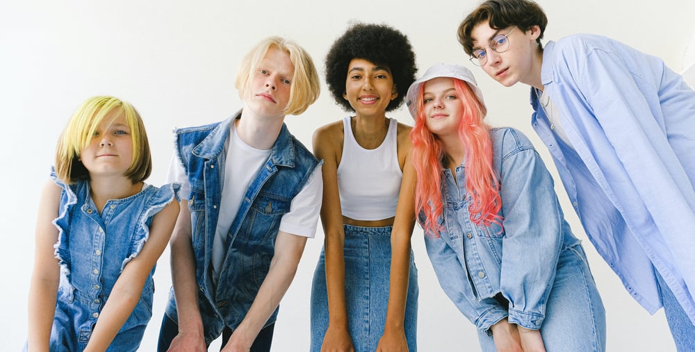 Fem personer lutar sig fram mot kameran mot en vit bakgrund.