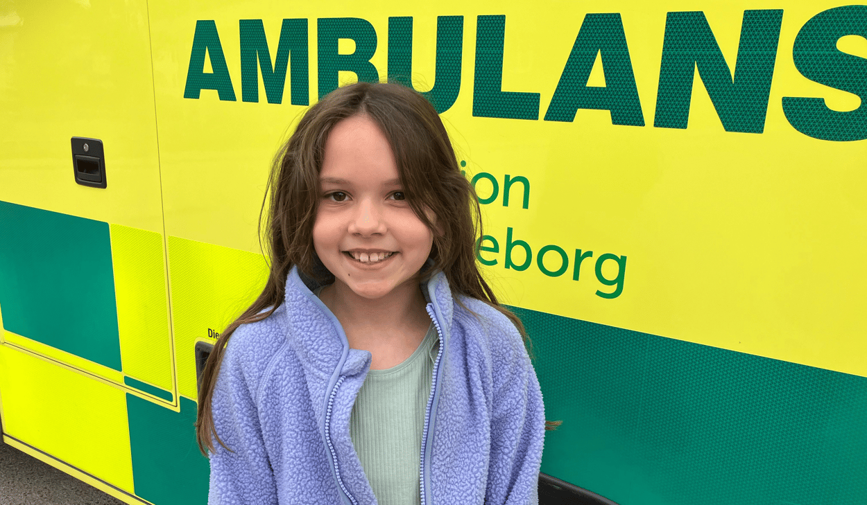En ung flicka står framför en ambulans.