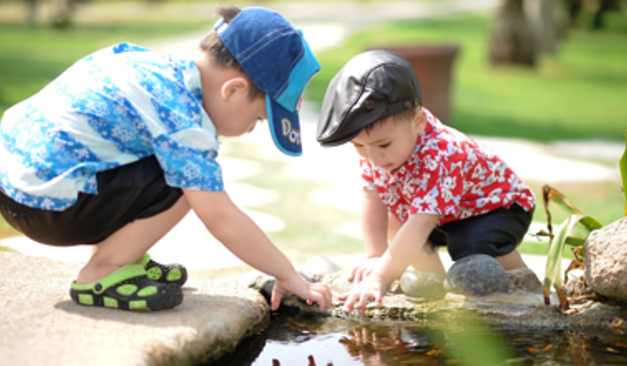 Två unga pojkar leker i en vattendamm.