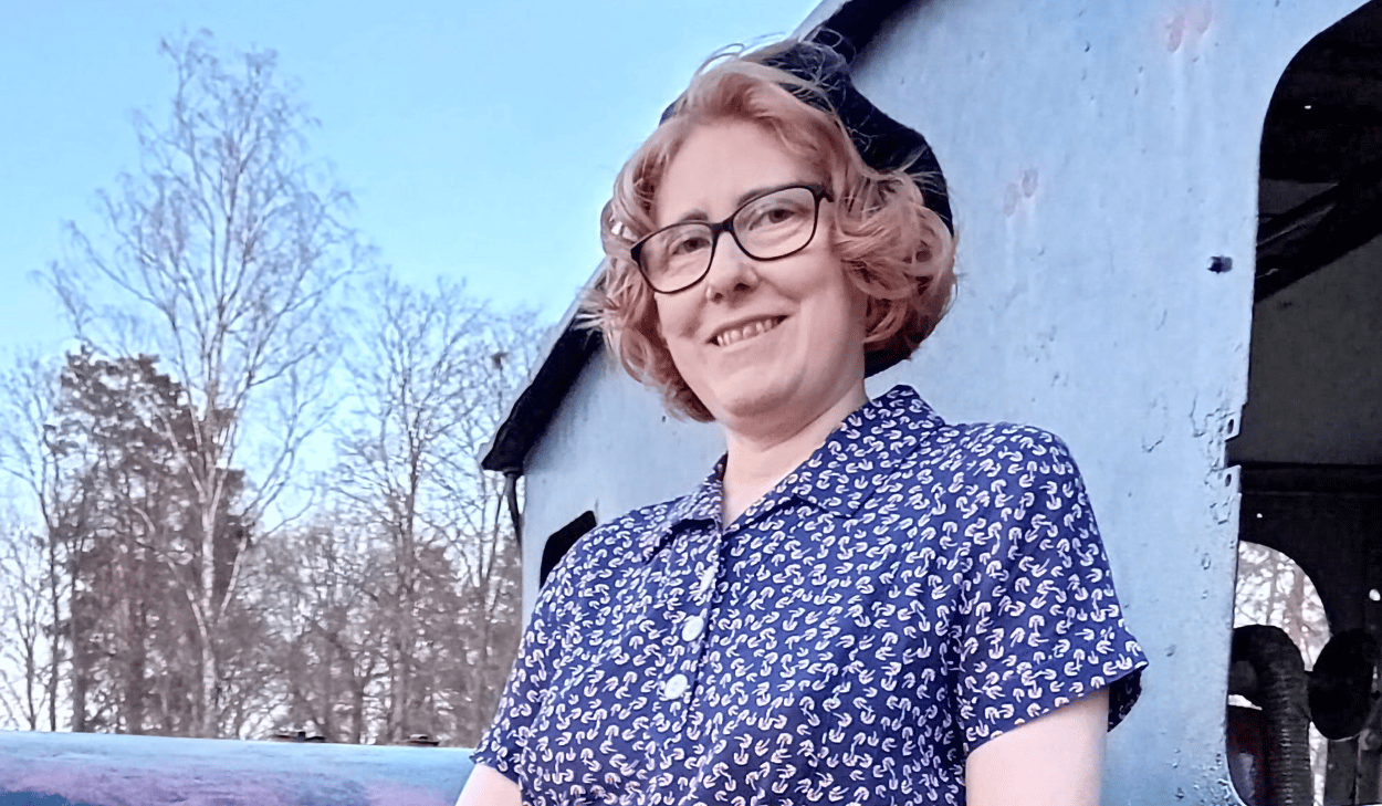 En kvinna i en blå klänning som lutar sig mot sidan av ett tåg.