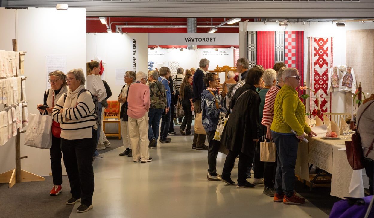 Många besökare samlade i området "VÄVTORGET", där vävda textilier och dukningar visas upp i olika montrar.