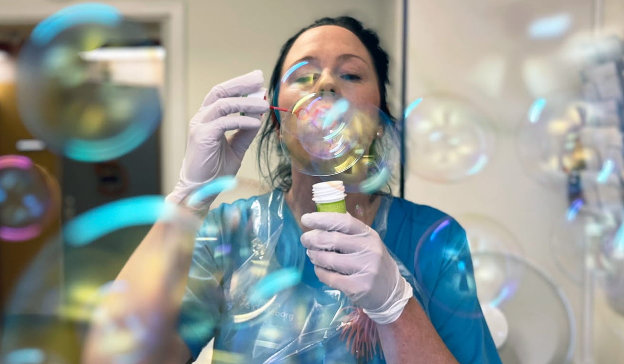 Barnsköterska Emma Good blåser såpbubblor. 