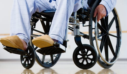 En man sitter i rullstol i ett rum.