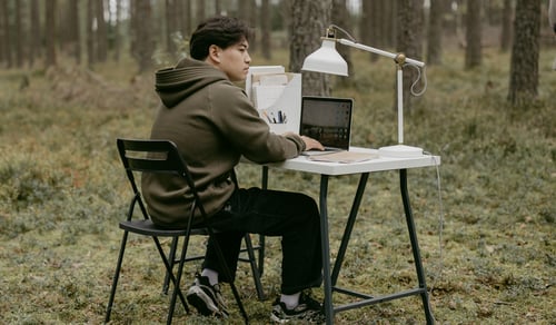 En person som sitter vid ett skrivbord med en bärbar dator.