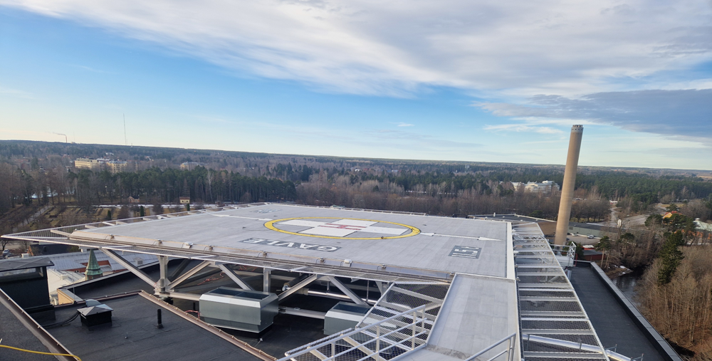 En flygbild &ouml;ver en helikopterflygplats med en byggnad i bakgrunden.