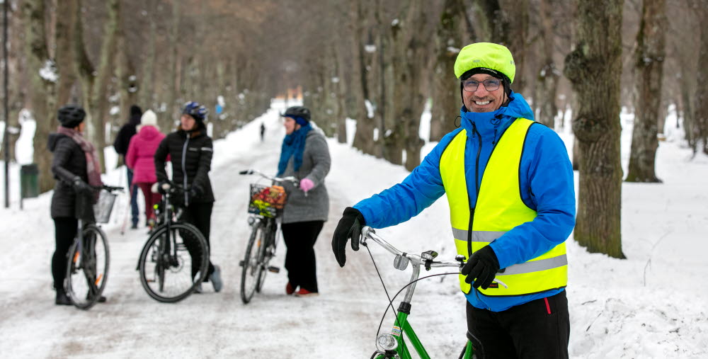 Flera personer står med sina cyklar på snötäckt cykelbana